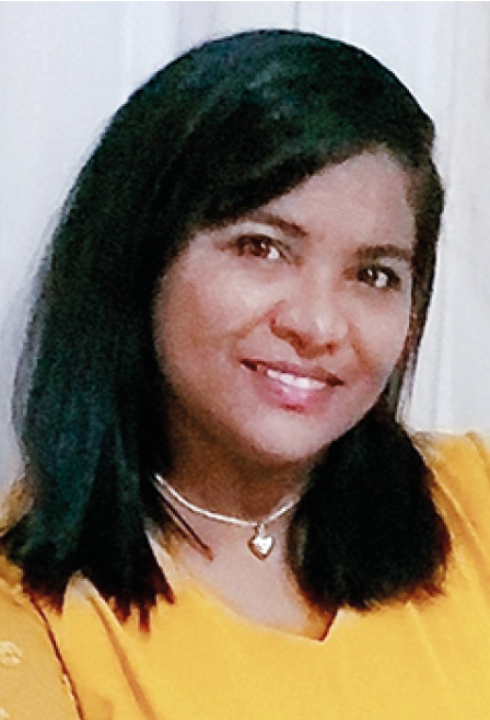 Fotografia com fundo branco mostra uma mulher preta, de cabelos lisos, cortados na altura dos ombros. Ela veste uma blusa amarela e sorri em nossa direção.